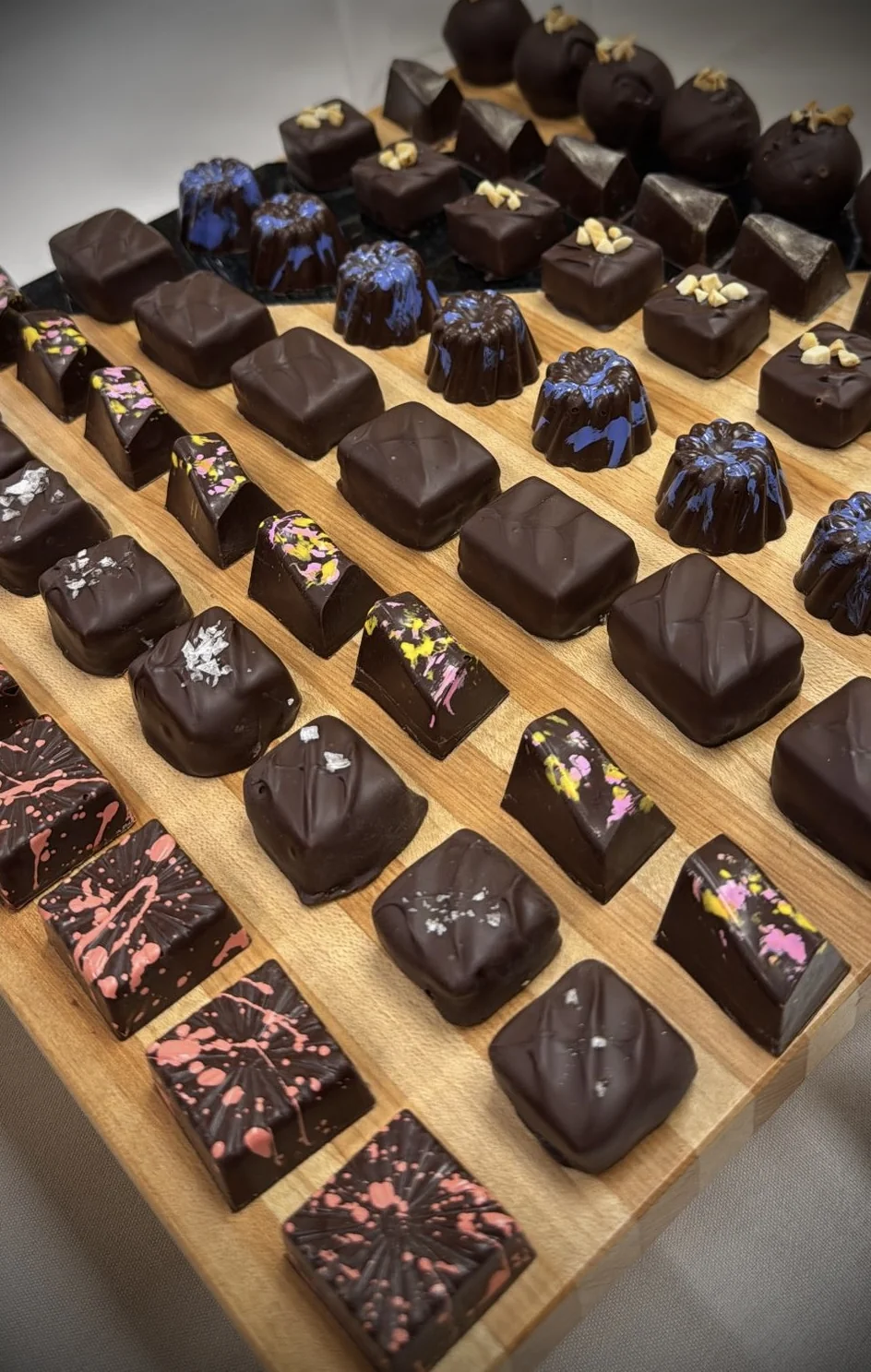 Bonbons d'Art — tableau of hand-painted dark chocolate bonbons with ganache and praliné fillings
